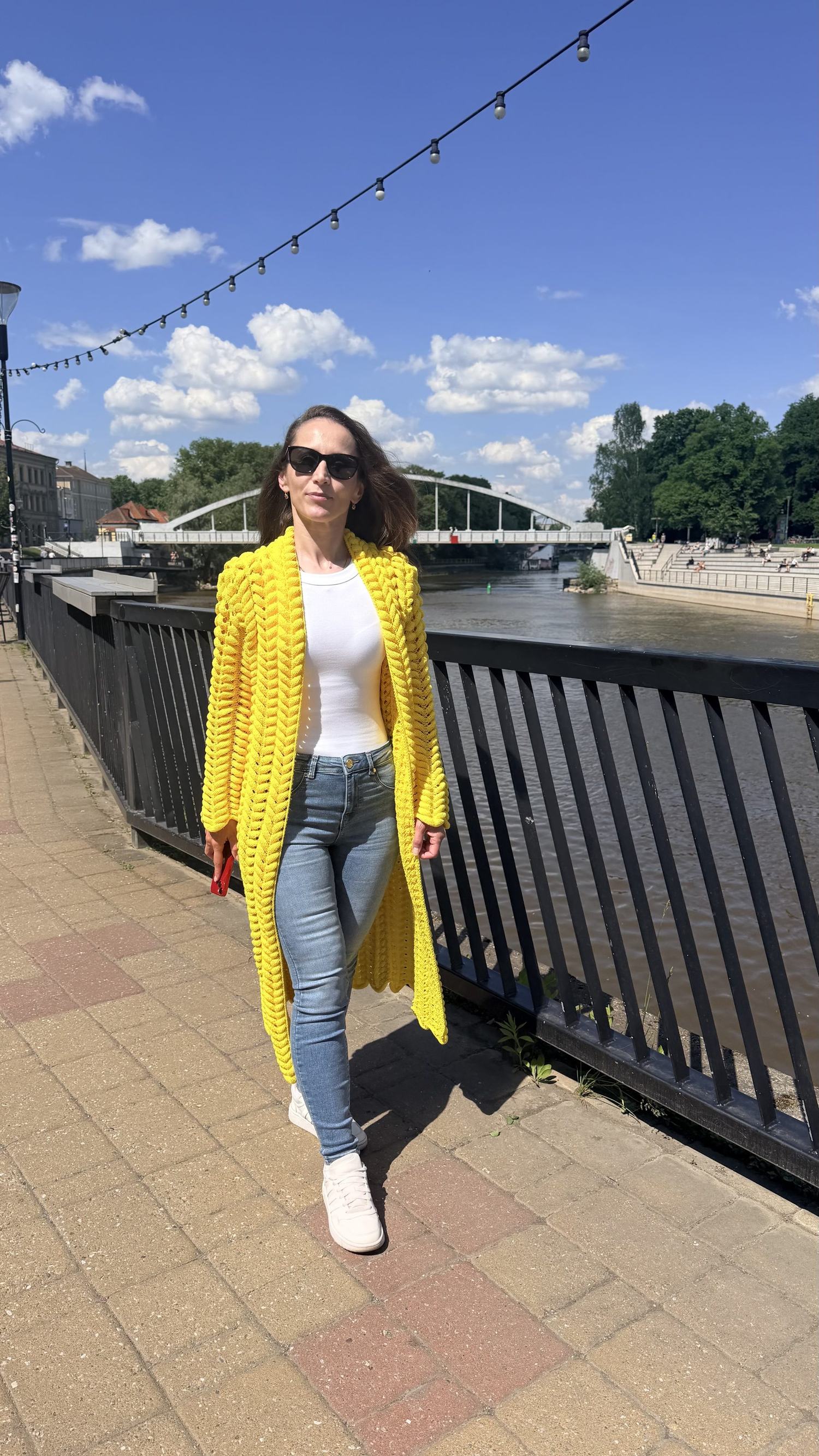The Lalo cardigan in bright yellow, worn on a riverside walk